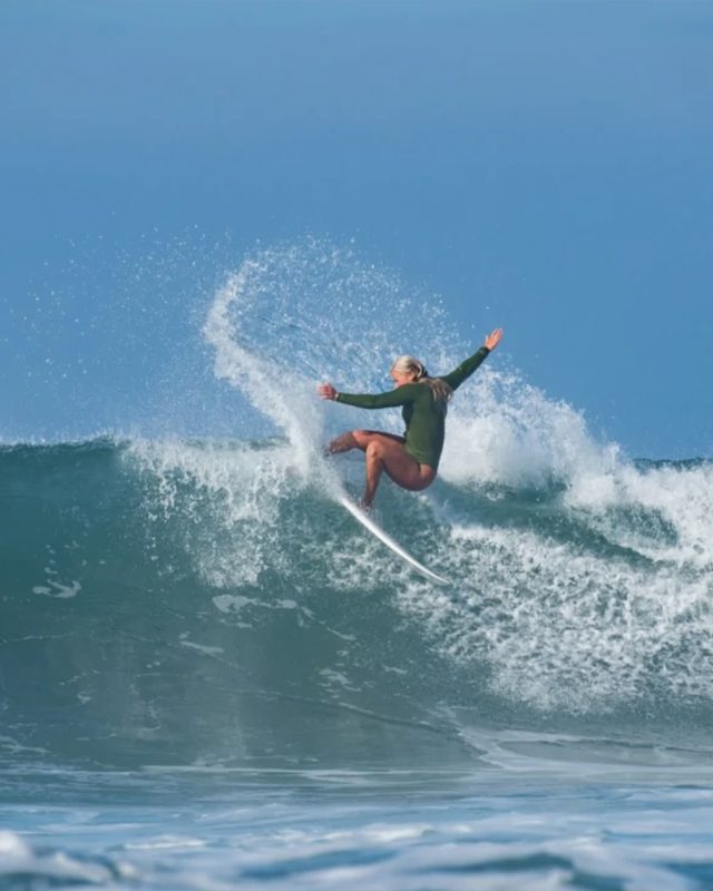 A surfer carving a turn on a blue wave